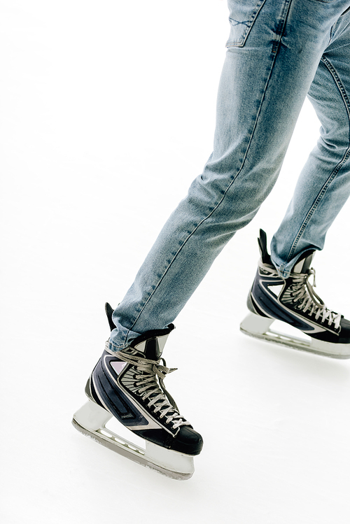 cropped view of man in jeans and skates skating on rink