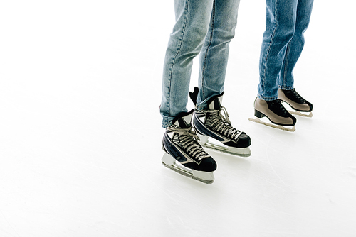 cropped view of young couple in skates skating on rink