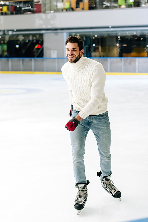 happy man in jeans and sweater skating on rink