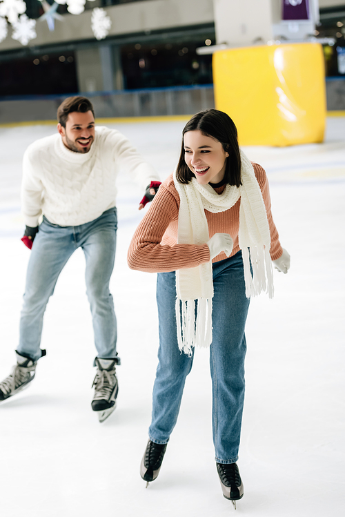 young positive couple having fun while skating on rink