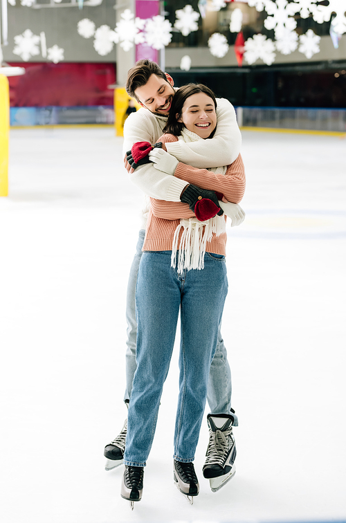 young smiling couple hugging and having fun on skating rink