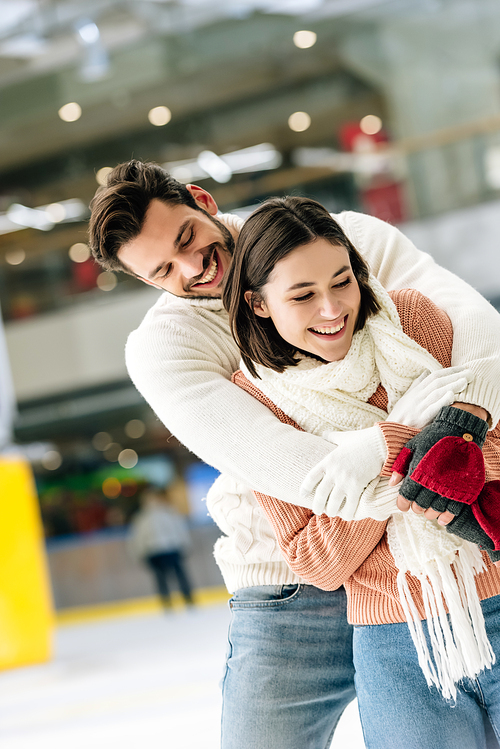 cheerful couple hugging and spending time on skating rink