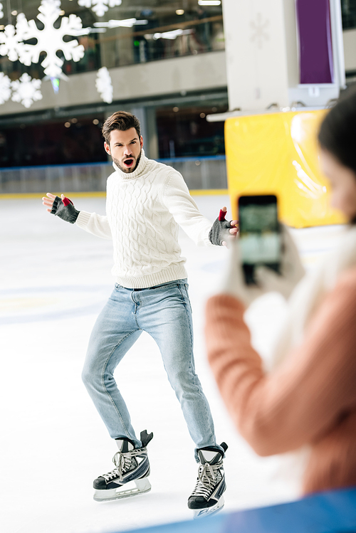 selective focus of woman taking photo of excited man on smartphone on skating rink