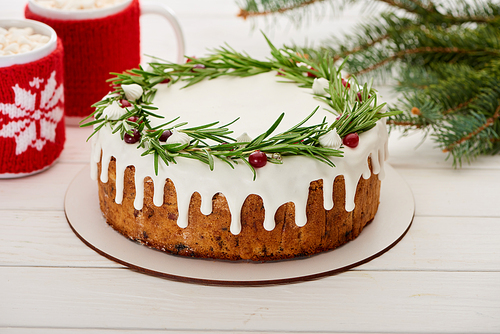 sweet christmas pie with icing and two cups of cocoa with marshmallows on white wooden table