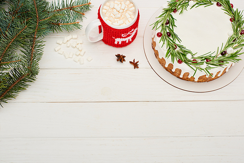 top view of christmas pie on white wooden table with cup of cocoa with marshmallows and spruce branches