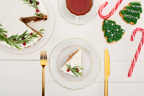 top view of christmas pie, tea, cookies and candy canes on white wooden table