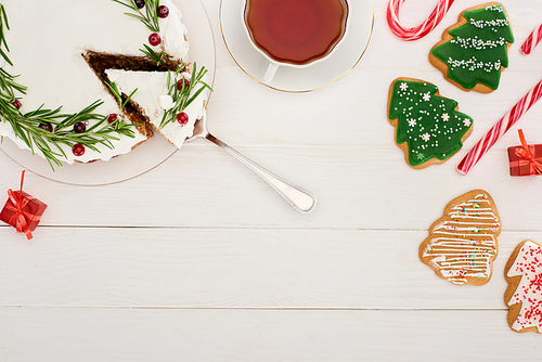 top view of christmas pie, cup of tea and christmas tree cookies on white wooden table