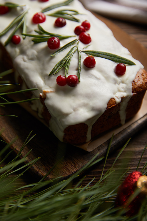 selective focus of traditional Christmas cake with cranberry near pine branch