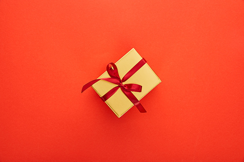 top view of golden gift box on red background
