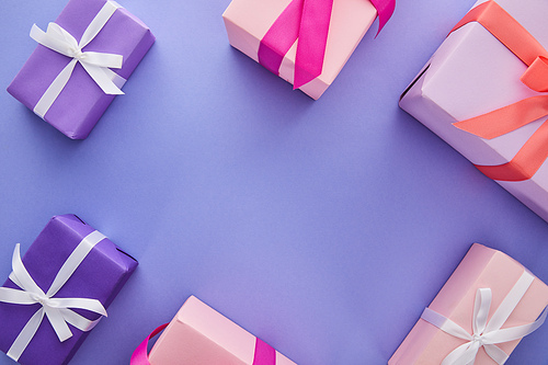 top view of colorful presents with bows on purple background with copy space