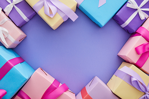 top view of colorful presents with bows on purple background with copy space