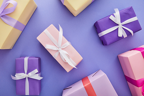 top view of colorful presents with bows scattered on purple background
