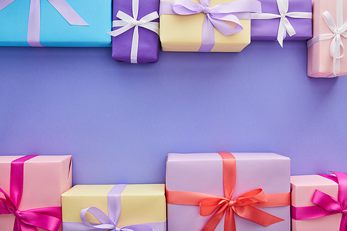 flat lay with colorful gifts with bows on purple background with copy space