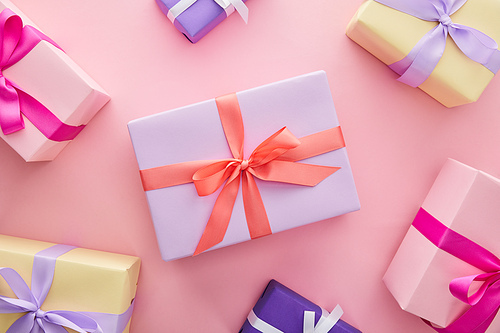 top view of colorful gift boxes with ribbons and bows on pink background