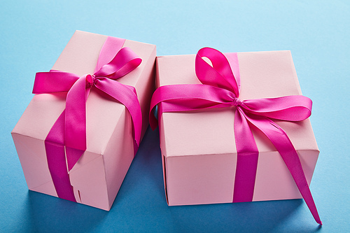 pink colorful gift boxes with crimson ribbons and bows on blue background