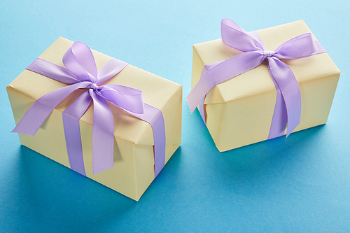 yellow colorful gift boxes with violet ribbons and bows on blue background