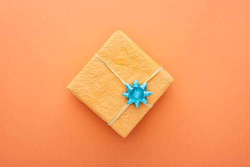 top view of gift box with blue bow isolated on orange