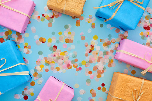 top view of colorful wrapped gifts near confetti on blue
