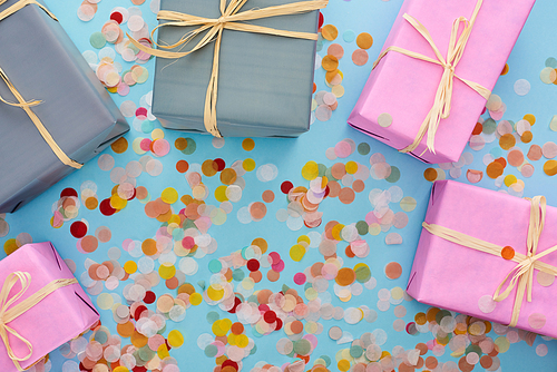 top view of colorful wrapped presents near confetti on blue