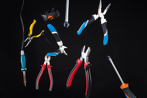 Set of tools with screwdriver and pliers levitating in air isolated on black