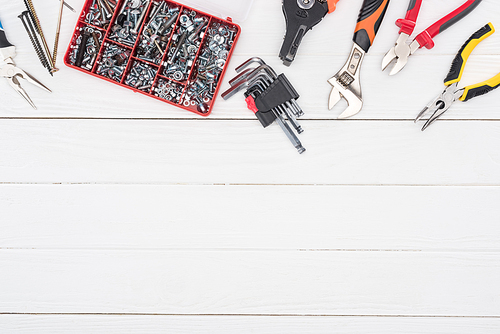 Top view of tool box with pliers and wrench on white wooden background