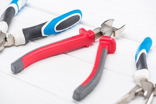 Selective focus of pliers on white wooden background