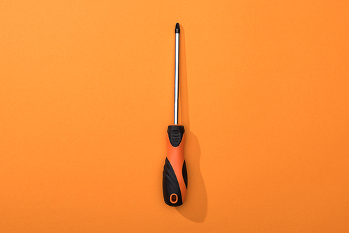 Top view of screwdriver on orange background
