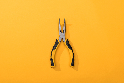 Top view of pliers on yellow background