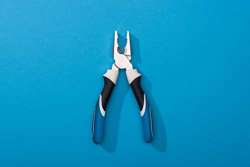 Top view of pliers on blue surface with copy space
