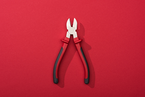 Top view of pliers with shadow on red background