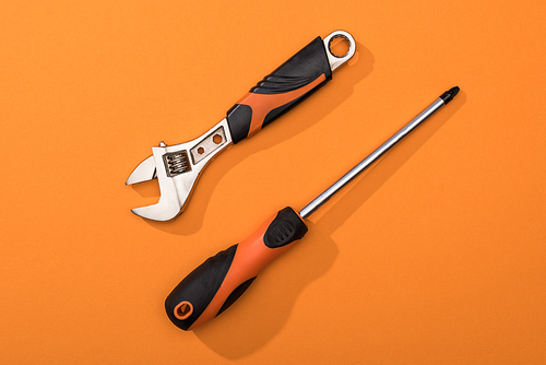 Top view of wrench and screwdriver on orange surface