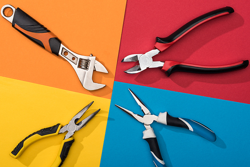 Top view of wrench and pliers on colorful background