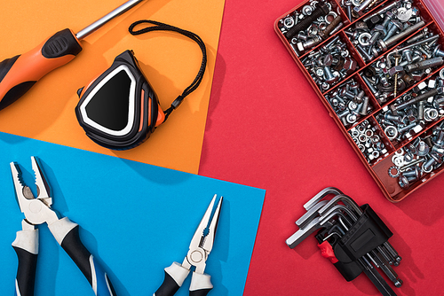 Top view of tool set with pliers and measuring tape on colorful background