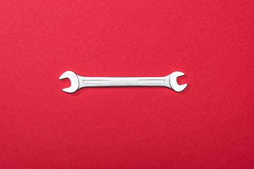 Top view of metal wrench on red background