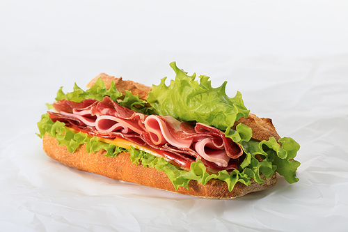 fresh sandwich with lettuce, ham, cheese, bacon and tomato on textured white background