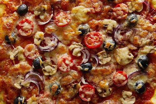 Top view of delicious pizza with cherry tomatoes, olives and Parmesan