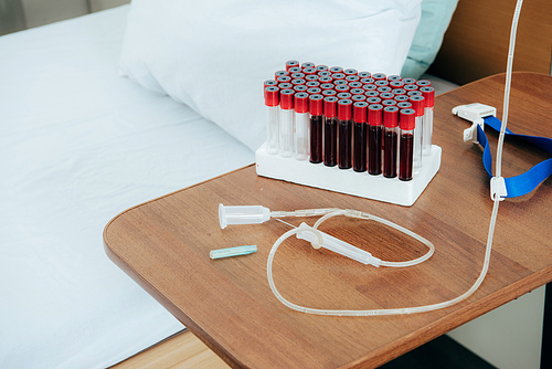 bed with pillow, blood test tubes, tourniquet and syringe in hospital ward