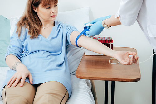 partial view of doctor using tourniquet for blood test in hospital