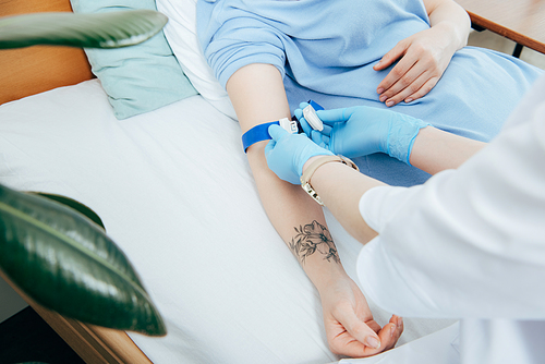 partial view of doctor using tourniquet for blood test in hospital