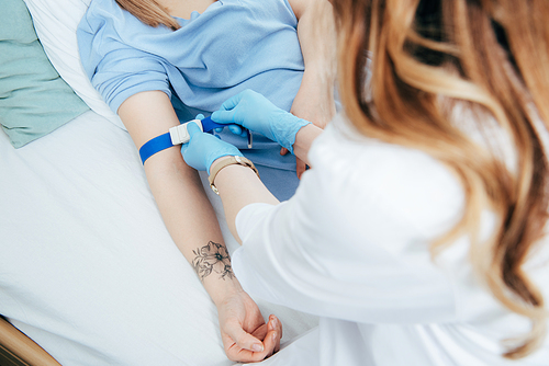 partial view of doctor using tourniquet for blood test in hospital