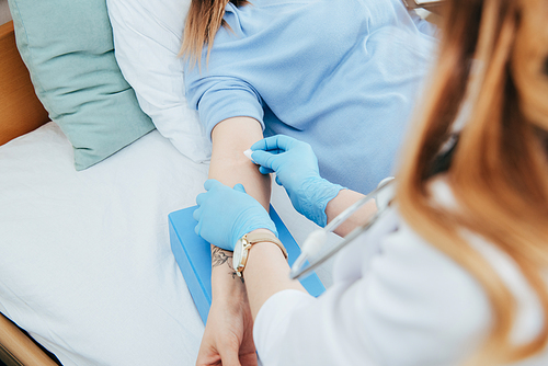 partial view of doctor in latex gloves preparing patient for injection