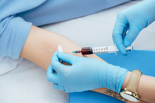 cropped view of donor and doctor with syringe obtaining blood sample