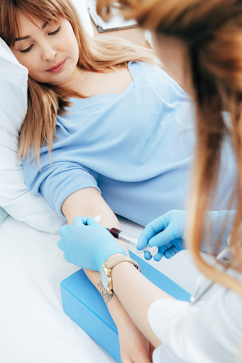 cropped view of donor and doctor with syringe obtaining blood sample