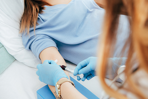 cropped view of donor and doctor with syringe obtaining blood sample