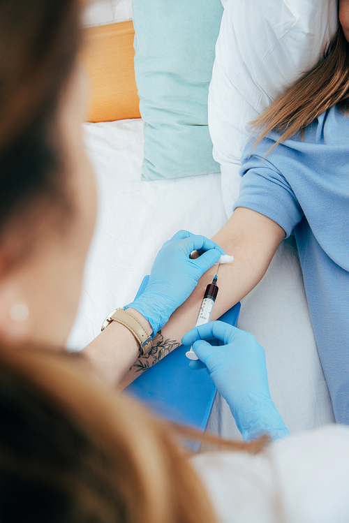 cropped view of donor and doctor with syringe obtaining blood sample