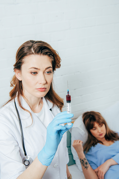 donor lying on bed and doctor holding syringe with blood sample