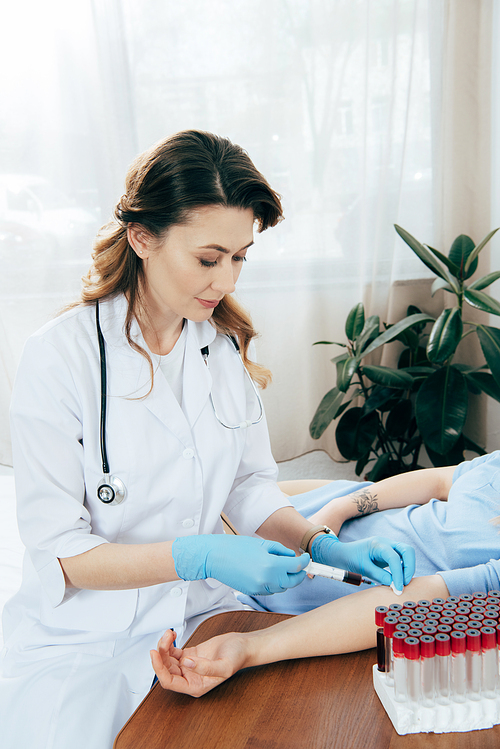 cropped view of donor and doctor with syringe obtaining blood sample