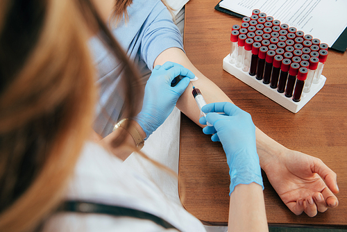 cropped view of donor and doctor with syringe obtaining blood sample