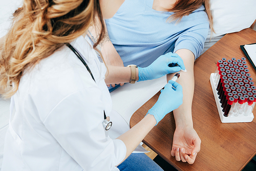 cropped view of donor and doctor with syringe obtaining blood sample