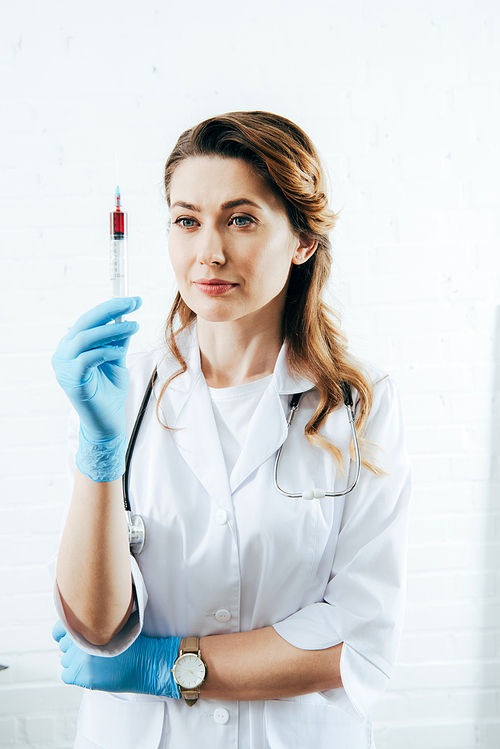 doctor in latex gloves holding syringe with blood sample